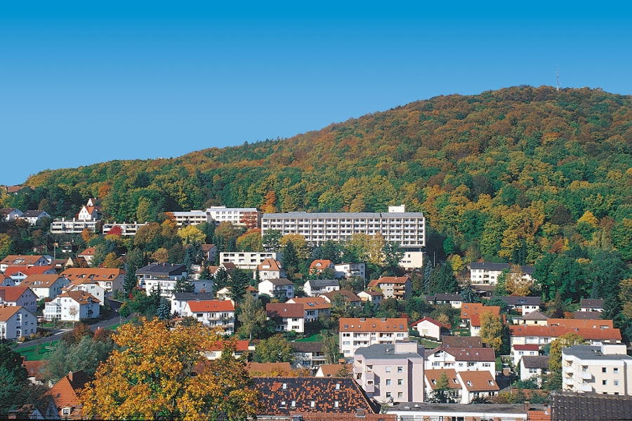 Ansicht der Marbachtalklinik Bad Kissingen, eingebettet in einer herbstlichen Waldlandschaft in reizvoller Hanglage.